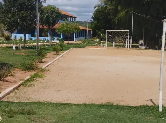 Campo de areia com traves, cercado por gramado e árvores